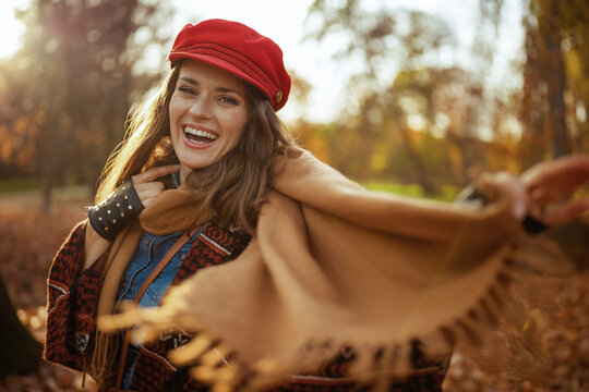 Hello autumn. smiling modern woman in red hat with scarf and gloves in the city park. - Powered by Adobe