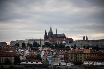 Obraz premium tyn church in prague, historic rooftops and church towers, likely in Prague's Malá Strana, Lesser Town, district. A prominent feature is a building with a distinctive green-domed tower 