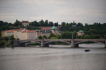 view of the river, Vltava River in Prague. In the foreground, the water of the river is visible, with a small, flat-topped tourist boat 