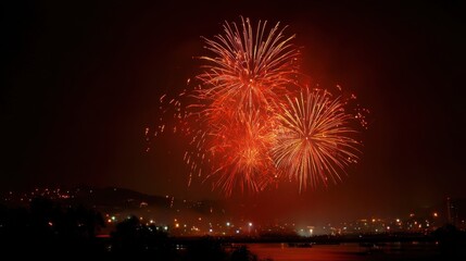 A fireworks display is lit up in the night sky. The fireworks are red and are scattered across the sky. Scene is festive and celebratory