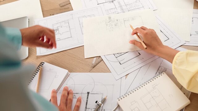 Professional engineer team discussion about house design on meeting table with architectural equipment and building blueprint scatter around at modern office. Focus on hand. Closeup. Delineation.