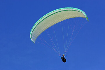 Paraglider flying in a blue sky	