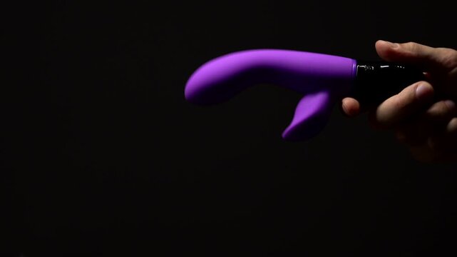 Purple rabbit vibrator for sexual pleasure and enjoyment.
Hand vibrator for orgasm on black isolated background.
Adult sex toys