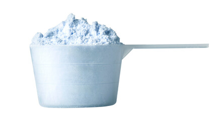 Measuring scoop overflowing with laundry detergent powder on white background