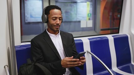 Businessman listening music and browsing smartphone on subway - Powered by Adobe