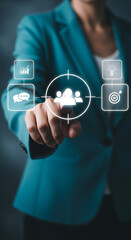 Photo of a business woman is pointing to a target audience icon with business strategy icons around it, representing business goals