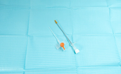 14G IV cannula with needle removed, placed side by side on a blue sterile background, featuring an orange one-way valve cap for intravenous access and rapid infusion.