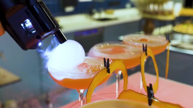 Bartender decorates a cocktail with a transparent smoky bubble, creating an impressive drink presentation at the bar counter