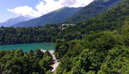 Lush green forest surrounds a turquoise lake nestled amongst mountains.