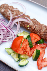 Kebab with vegetables and onions on a wooden table