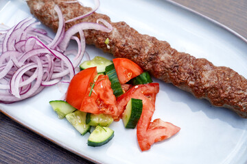 Kebab with tomatoes and onions on a white plate