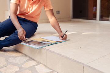 Student taking notes on campus staircase, studying for upcoming academic test