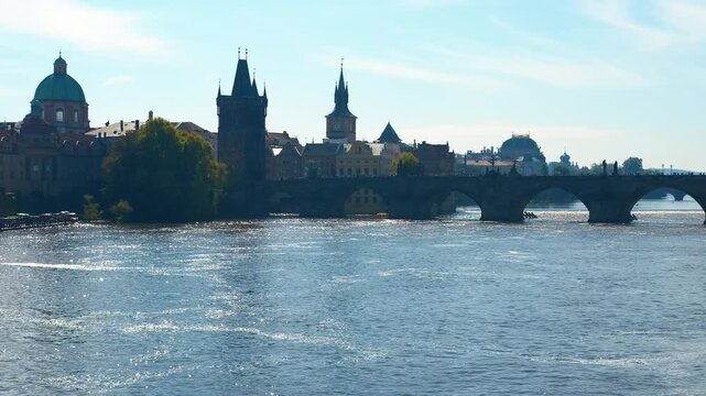 Vltava river flowing under charles bridge in prague. Gentle waves ripple the surface of the vltava river as it flows beneath the iconic charles bridge, showcasing the historic architecture of prague