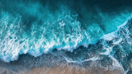 Fototapeta premium Vibrant turquoise waves crash against the sandy shore under clear blue skies. Sunlight glimmers on the water, creating a serene and inviting coastal atmosphere.
