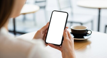 A woman from behind in a cafe setting, using a smartphone with a blank white screen (mockup).