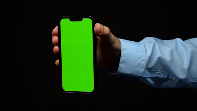 Smartphone mockup with green blank screen on black isolated background in male hand.
Green display on mobile phone close-up.
Chromakey and background replacement