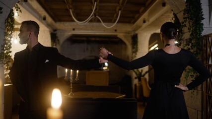 Professional tango dancers practicing intimate choreography, moving with passion in candlelight-illuminated studio, showcasing graceful connection between performers