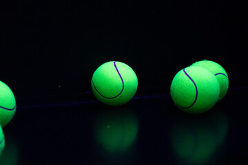 Vibrant green tennis balls on reflective surface