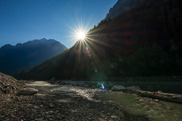 A picturesque view of a mountain river against the backdrop of the sky and mountains during sunset....
