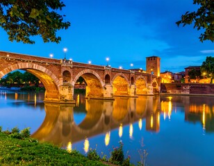Obraz premium Ancient stone bridge at twilight, reflected in still river