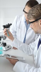 Medical researchers examine laboratory samples under a microscope and digital tablet during a collaborative scientific study. Medicine and science, teamwork concept