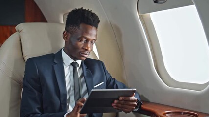 focused african american businessman on plane with tablet - Powered by Adobe
