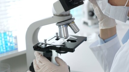 White gloved hands of scientist professional adjusting a microscope in a bright laboratory, emphasizing precision and focus in scientific research. Medicine, healthcare and science concept