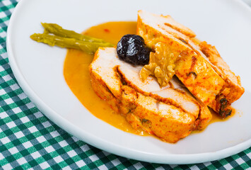 Plate of appetizing baked turkey breast with prunes and spicy sauce