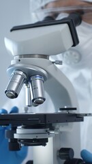 Close up of medical virologist in a hazmat suit, mask, and gloves, diligently working at a microscope in a laboratory researching viruses. Medicine and science concept