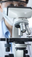 Scientist wearing lab coat and protective glasses using a modern microscope in a laboratory setting, conducting research and experiments in a scientific environment. Health care and science concept