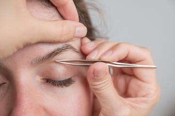 Caucasian woman undergoing eyebrow correction procedure. 