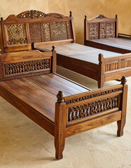 A collection of intricately carved wooden "angareb" (traditional beds) of various sizes, displayed on a textured, earthy background.