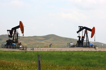 Three pumpjacks in hay field Saskatchewan Canada