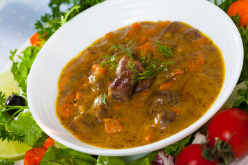 Chicken heart goulash served in ceramic bowl with vegetables