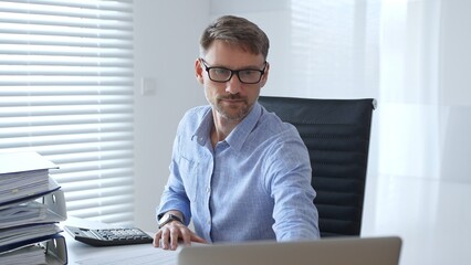 Male professional accountant calculating invoices and managing bills while reviewing financial reports in an office setting. Audit and taxes theme in business