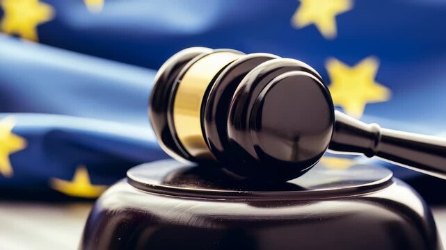 The image shows a gavel placed in front of a flag with yellow stars on a blue background, symbolizing legal authority and the enforcement of regulations and laws within international relations.
