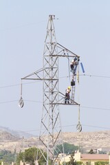 High-voltage tower repair technicians working suspended 20 meters above the ground.