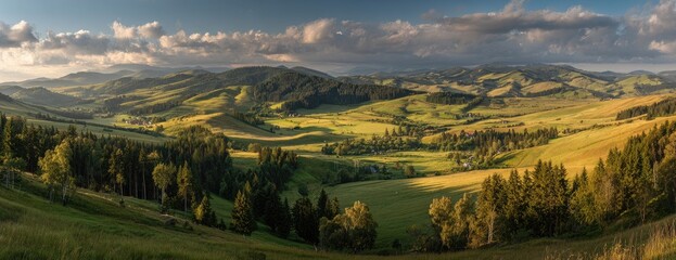 Panoramic view of a valley with rolling hills, lush greenery, and scattered forests under a partly cloudy sky at sunset