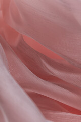 Close-up of pink semi-transparent fabric with soft texture and gentle folds, layered to create a flowing and elegant look; ideal for fashion, textile branding, wellness, and visual design projects