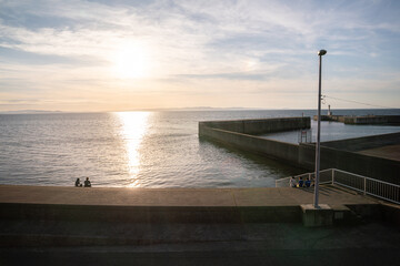 海岸で夕日を見つめる子供達