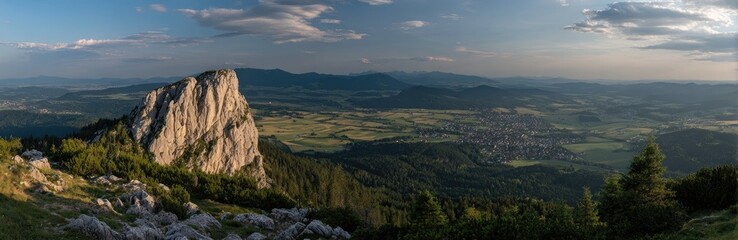 Fototapeta premium Panoramic mountain vista. Distant valley with town nestled amongst green hills. 