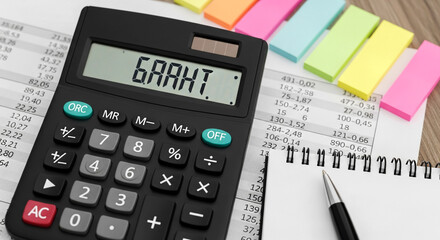 A close-up view of a calculator with 'GRANT' displayed on its screen situated on a pile of financial papers A notebook and pen are nearby with vibrant sticky notes adding a pop of color