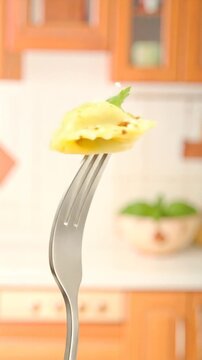 Close Up Ravioli on a Fork Garnished with Parsley with Wooden Cabinets and Tiles in The Background Kitchen Setting