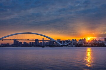 Modern bridge and city skyline at sunset in Shanghai.