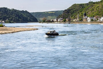 Obraz premium Scenic Rhine River view with boat and village.