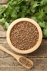 Fresh cilantro and coriander seeds on wooden table, top view