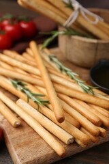 Delicious grissini sticks with rosemary on wooden table, closeup