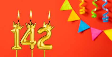 Number 142 birthday candle on an orange background with pennants