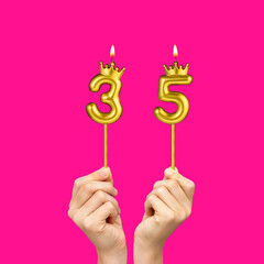 Hands holding number-shaped candles - Birthday number 35