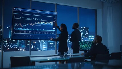 Business professionals analyzing financial data on a large screen in a modern office, strategic